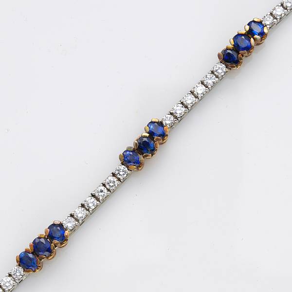 Appraisal: A diamond sapphire and fourteen karat bicolor gold line bracelet