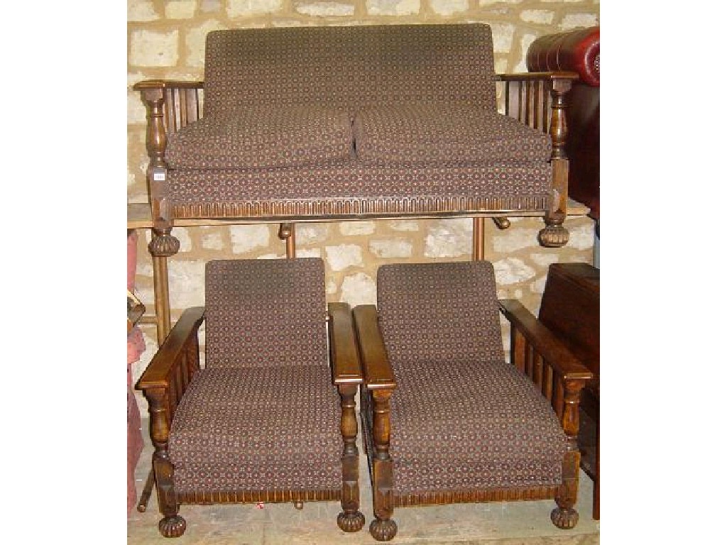 Appraisal: An Edwardian oak three piece suite with stylised upholstery square