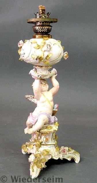 Appraisal: German porcelain oil lamp with cherub and extensive floral decoration