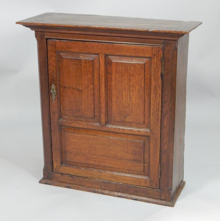 Appraisal: An oak wall cupboard with a moulded cornice above a