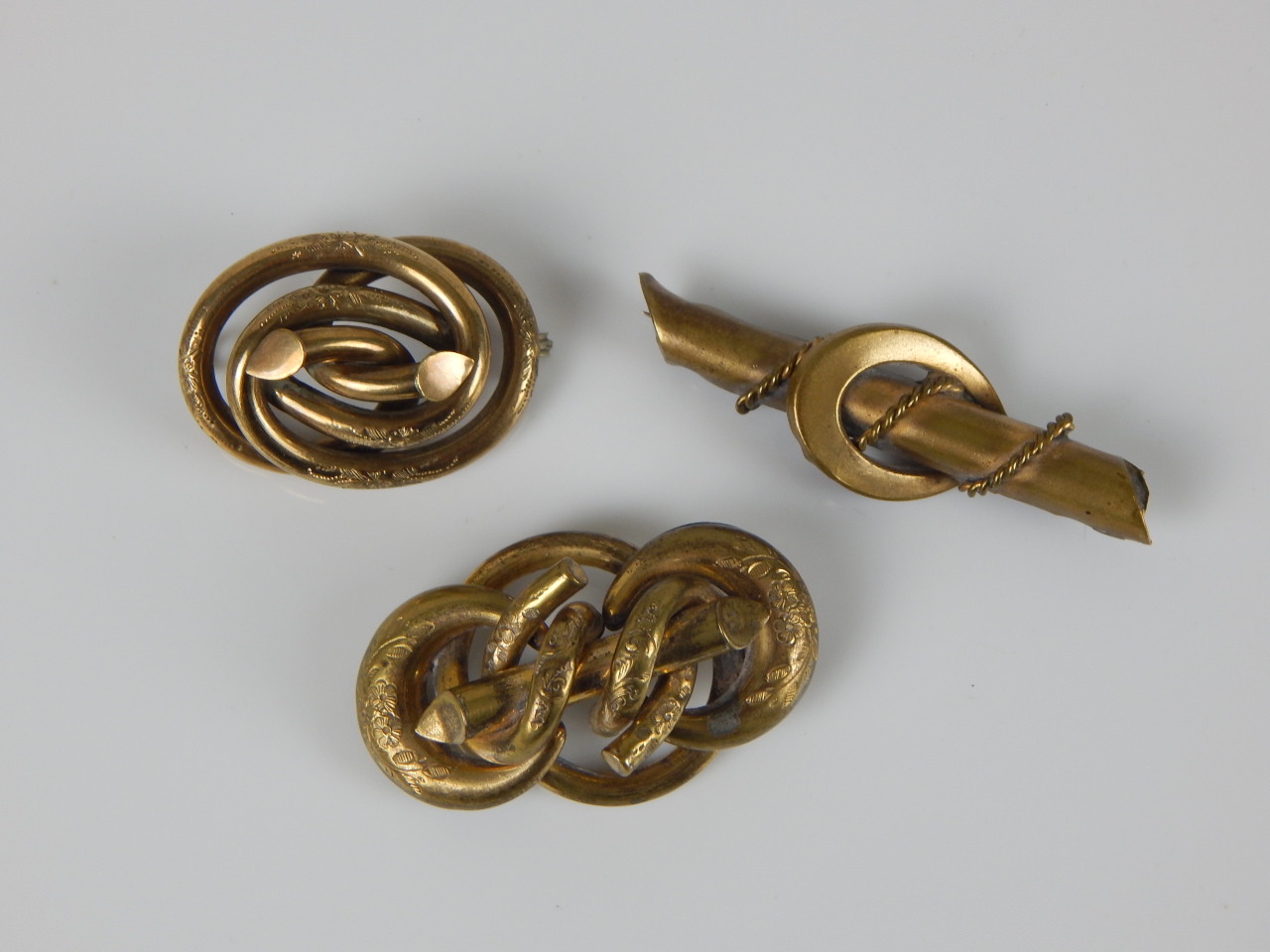 Appraisal: Three brooches each of knot form with floral motifs gold