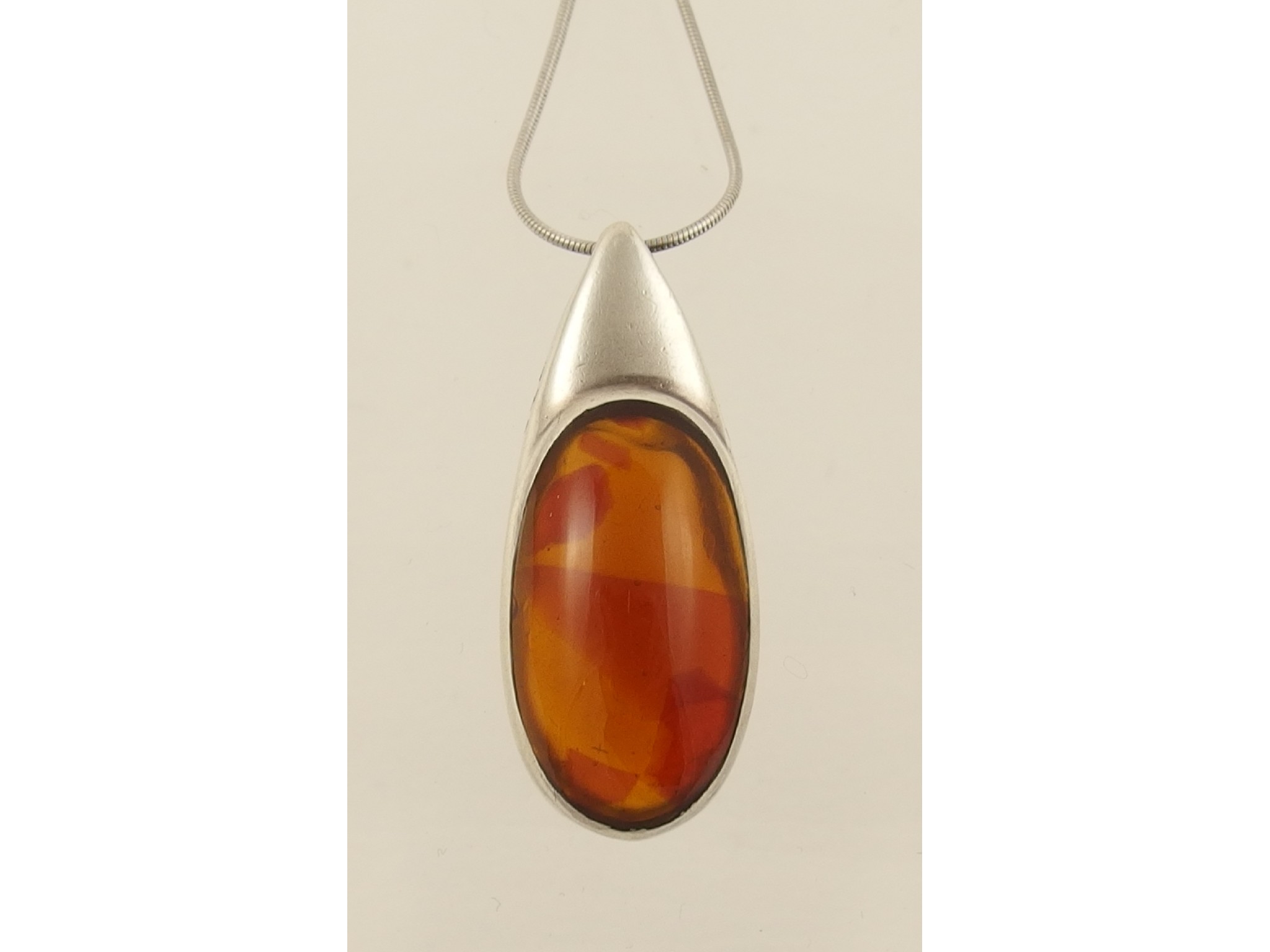 Appraisal: A silver mounted amber colour pendant with silver chain