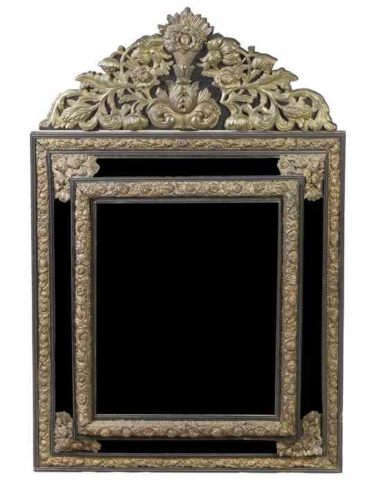 Appraisal: A Continental Pressed Brass and Ebonized Mirror the arched crest