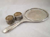 Appraisal: A silver backed hand mirror and two napkin rings one