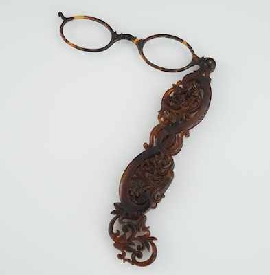 Appraisal: A Carved Tortoiseshell Lorgnette Carved reticulated case houses a swivel