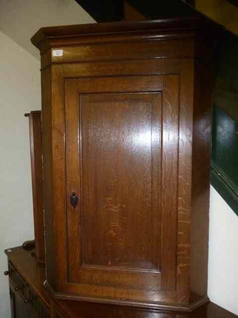 Appraisal: AN OAK HANGING CORNER CUPBOARD with single panelled door wide