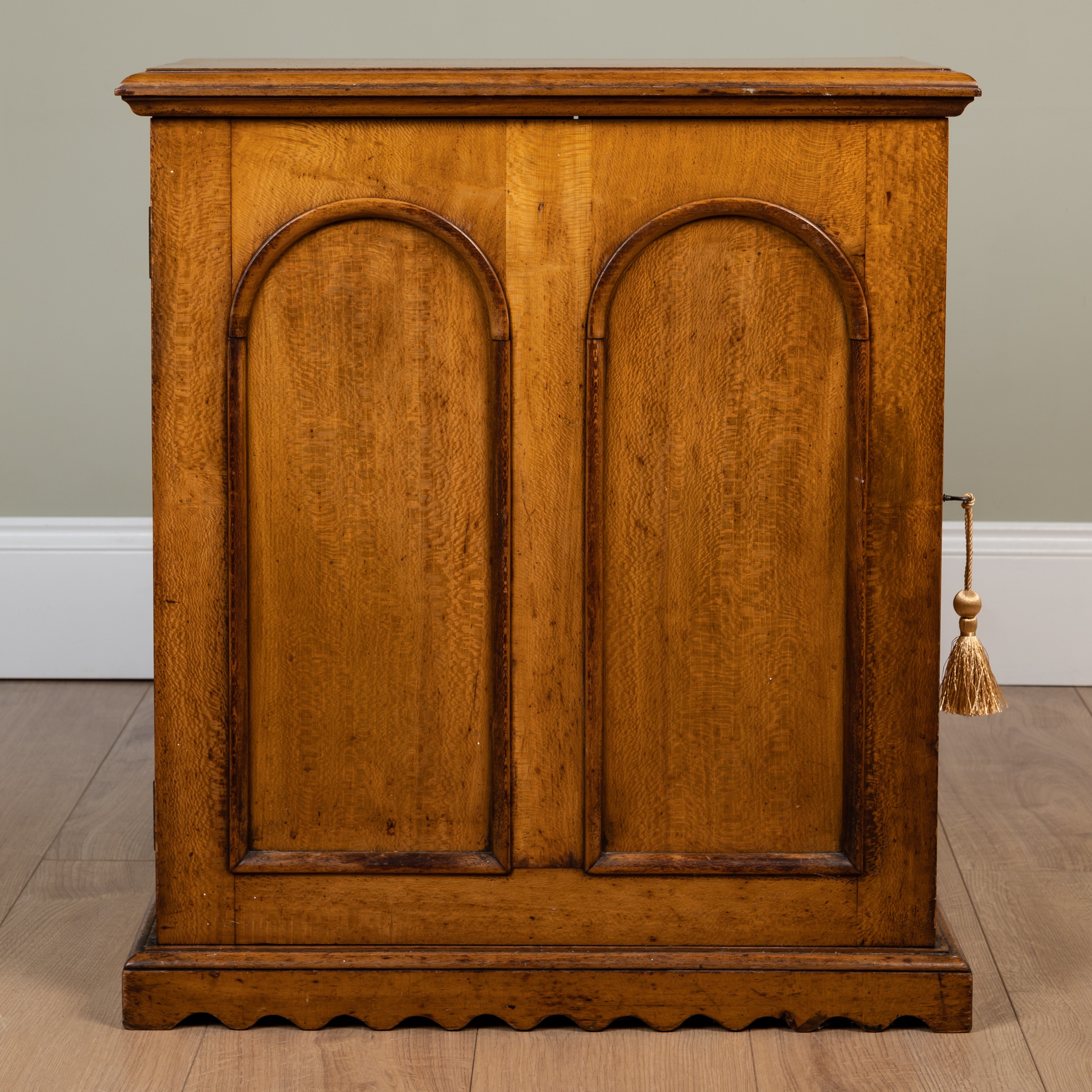 Appraisal: A th century satinwood cupboard with arched fielded panel door