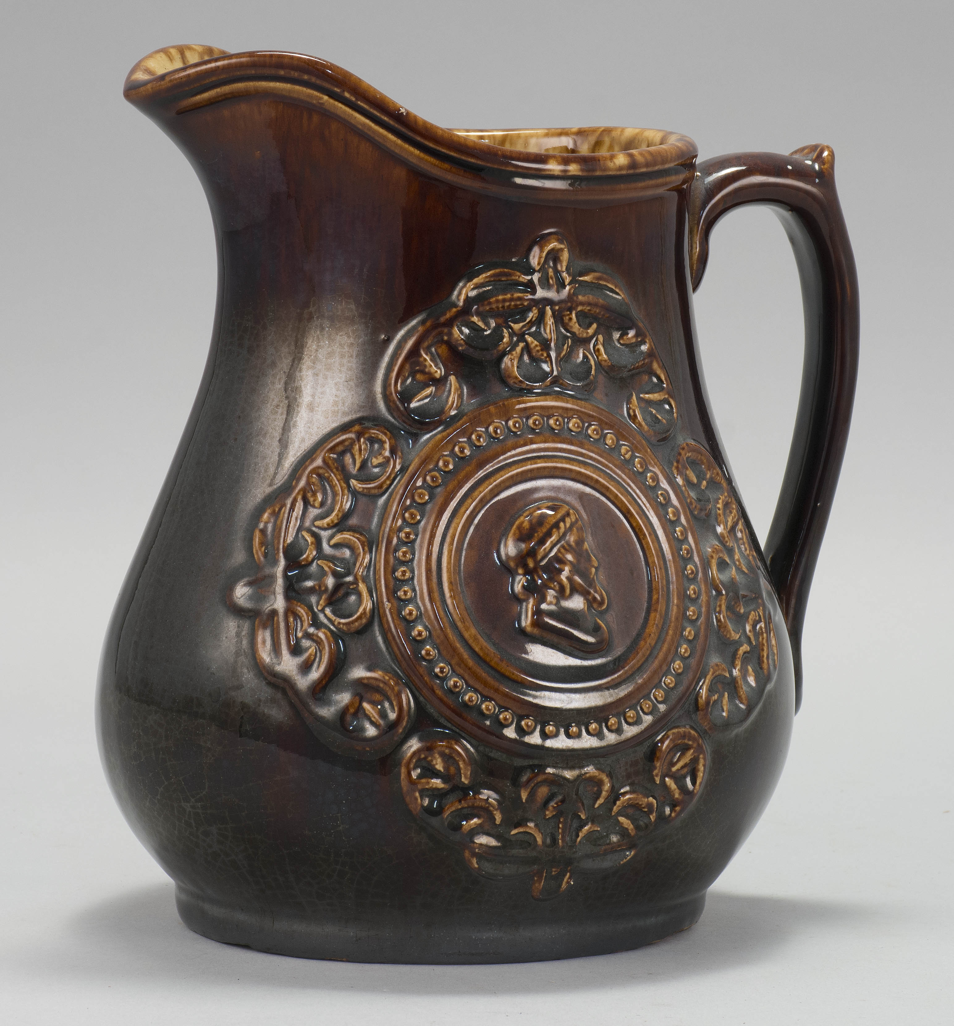 Appraisal: BENNINGTON POTTERY PITCHER Late th CenturyWith raised figural paneled decoration