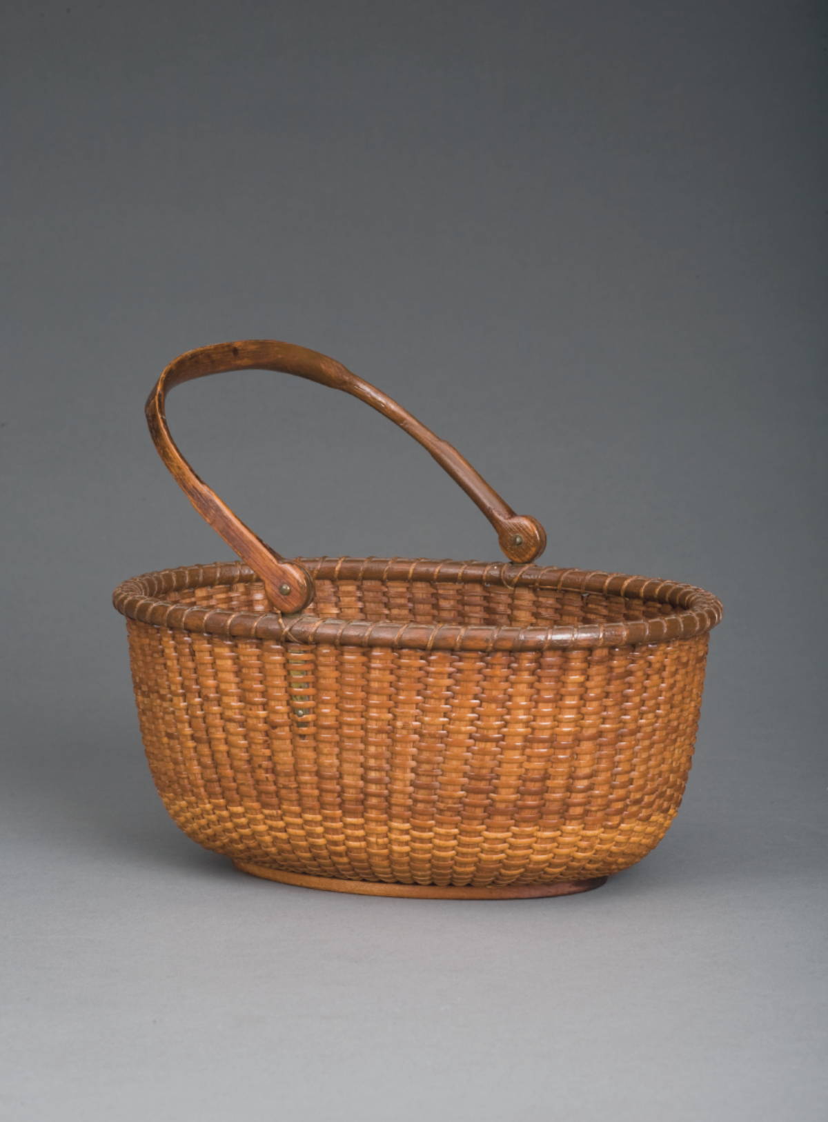 Appraisal: OVAL NANTUCKET BASKET WITH OLD PATINA AND SWING HANDLE The