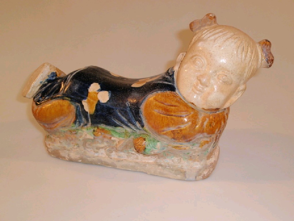 Appraisal: A Chinese terracotta figural pillow modelled as a recumbent young