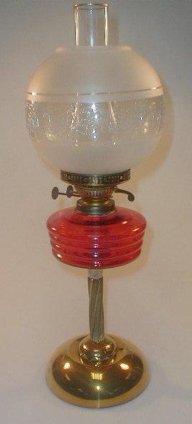 Appraisal: A brass oil lamp with a cranberry glass reservoir supported