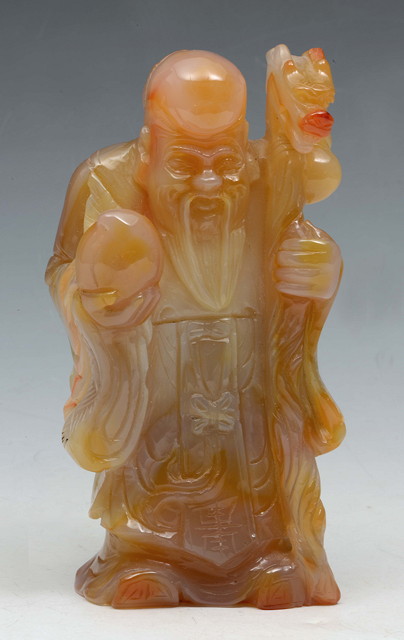 Appraisal: A CHINESE CHALCEDONY FIGURE OF AN IMMORTAL holding a peach