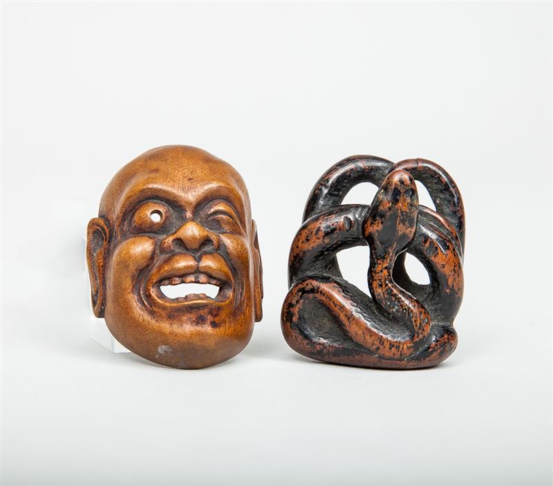 Appraisal: Two Japanese Carved Wood Netsuke Comprising a smiling face and