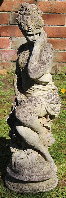 Appraisal: A CAST COMPOSITE GARDEN STATUE of a girl perched on