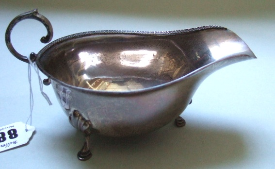 Appraisal: A silver sauce boat with a scrolling handle decorated rim