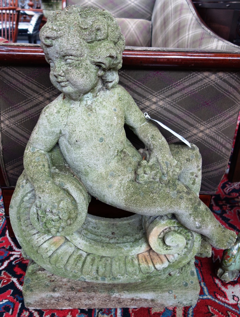 Appraisal: A pair of composite stone figures of reclining cherubs on