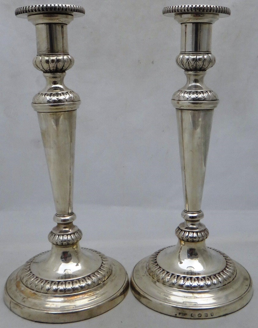 Appraisal: A pair of silver round candlesticks with loaf embossed bands