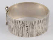 Appraisal: A silver bark effect bangle in the style of Gerald