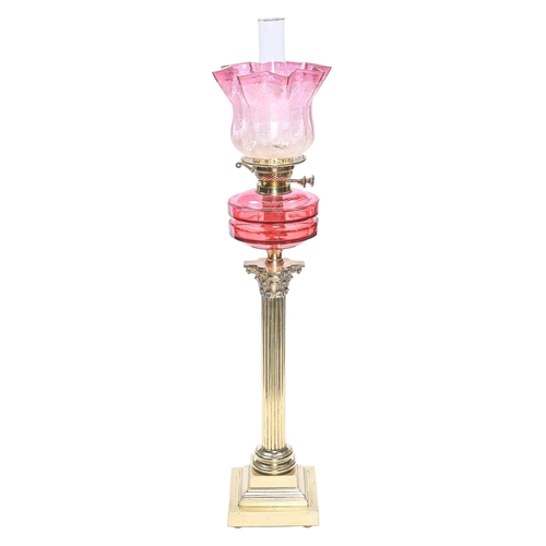 Appraisal: An Edwardian brass Corinthian column oil lamp with cranberry glass