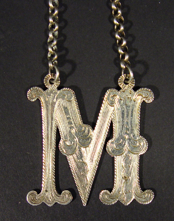 Appraisal: Silver decanter label letter 'M' on a chain with chased