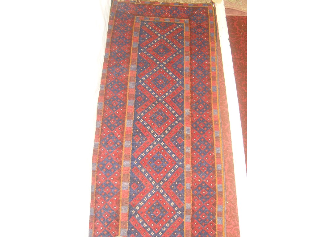 Appraisal: A red ground wool runner with repeating lozenge decoration in