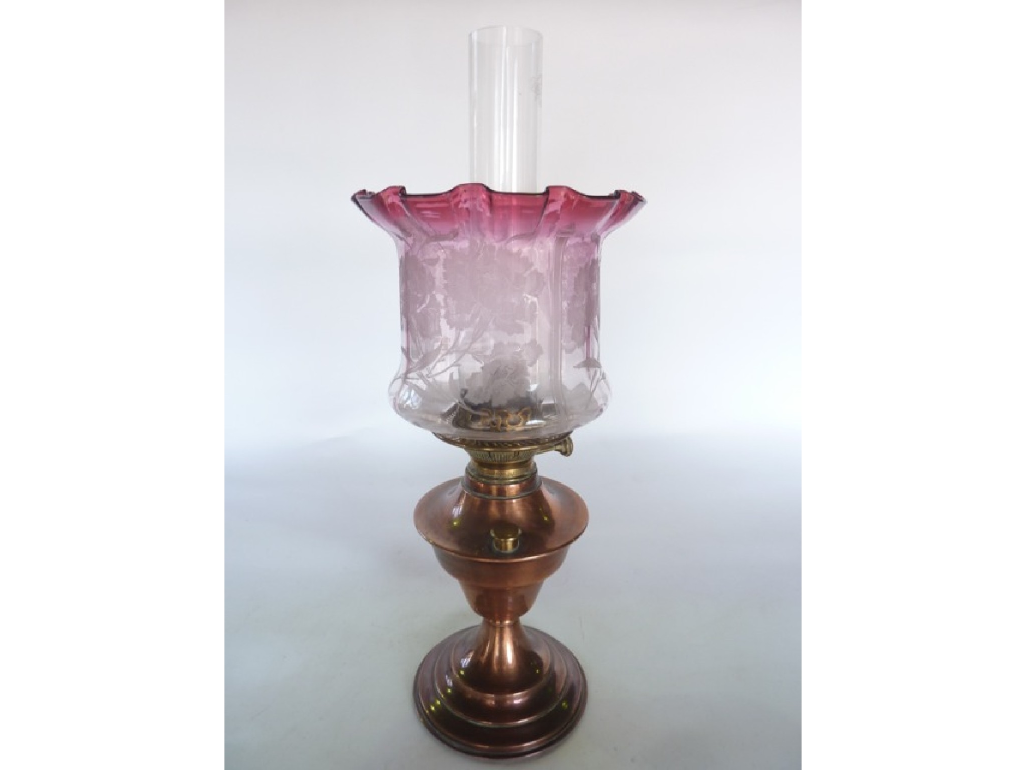 Appraisal: An oil burning lamp with copper fount accommodating a brass