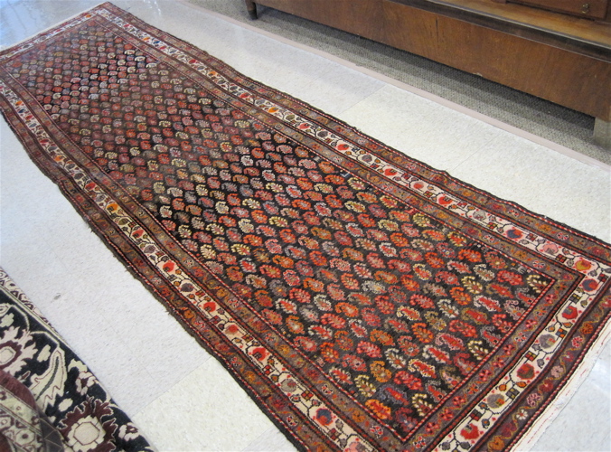 Appraisal: SEMI-ANTIQUE PERSIAN HALL RUG featuring a field of repeating boteh