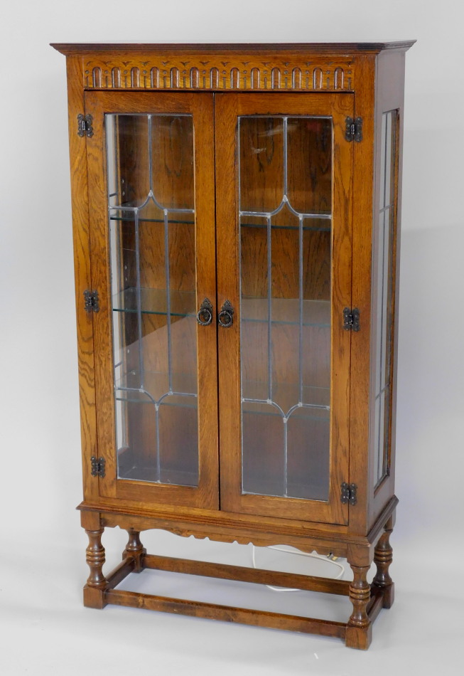 Appraisal: A mid thC oak display cabinet with a carved frieze