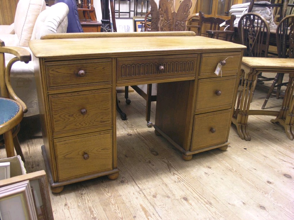 Appraisal: An Ercol-type light oak desk with seven short drawers ft