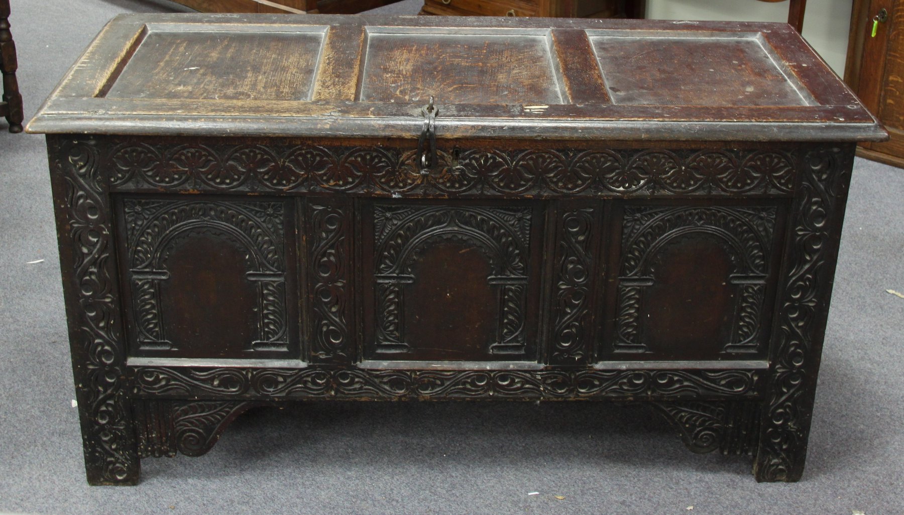 Appraisal: A carved oak chest with triple panelled hinged cover cm