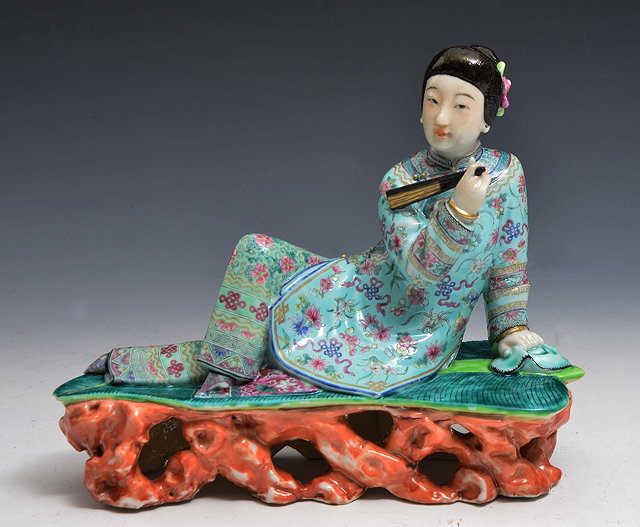 Appraisal: A CHINESE PORCELAIN FIGURE OF A RECLINING LADY holding a