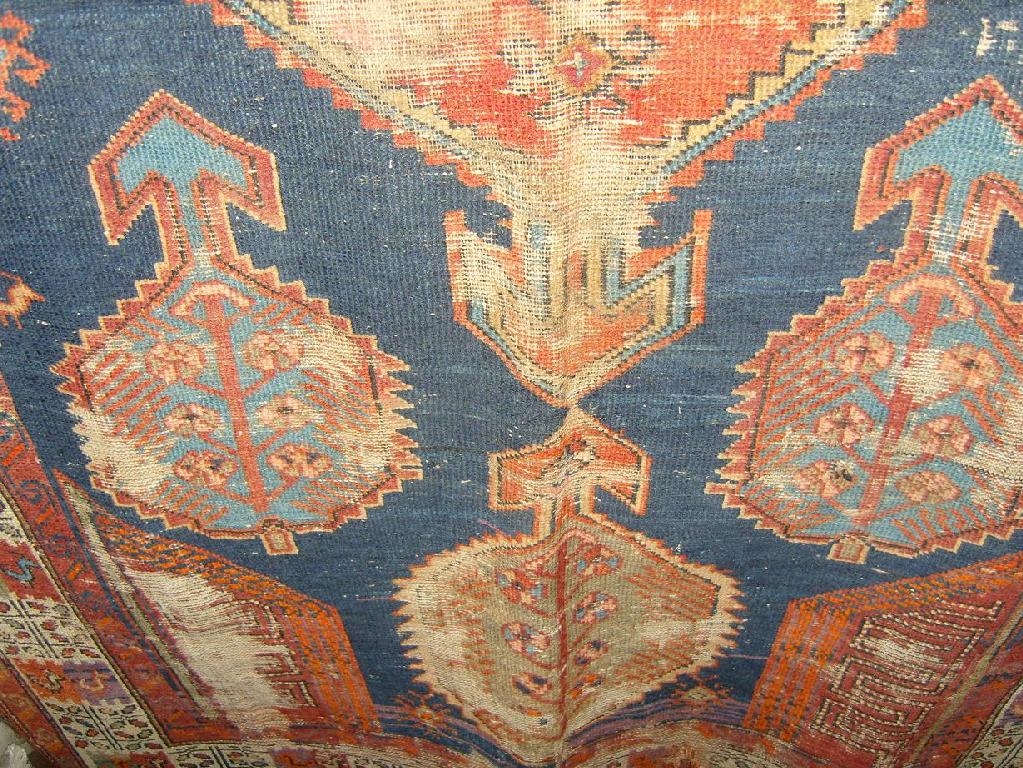 Appraisal: A worn Persian rug with blue field medallion centre within