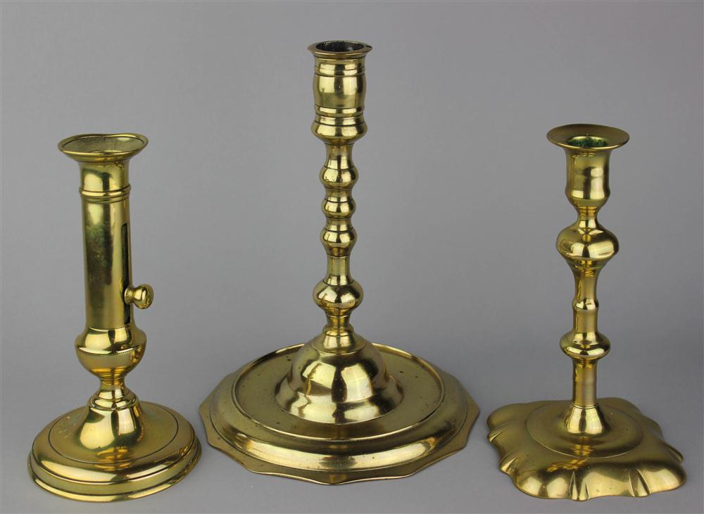 Appraisal: THREE BRASS CANDLESTICKS one variously knopped on a dished twelve-sided