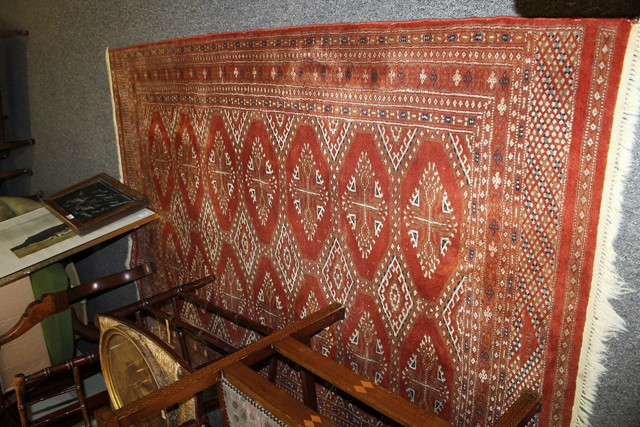 Appraisal: A RUST GROUND BOKHARA RUG with two rows of medallions