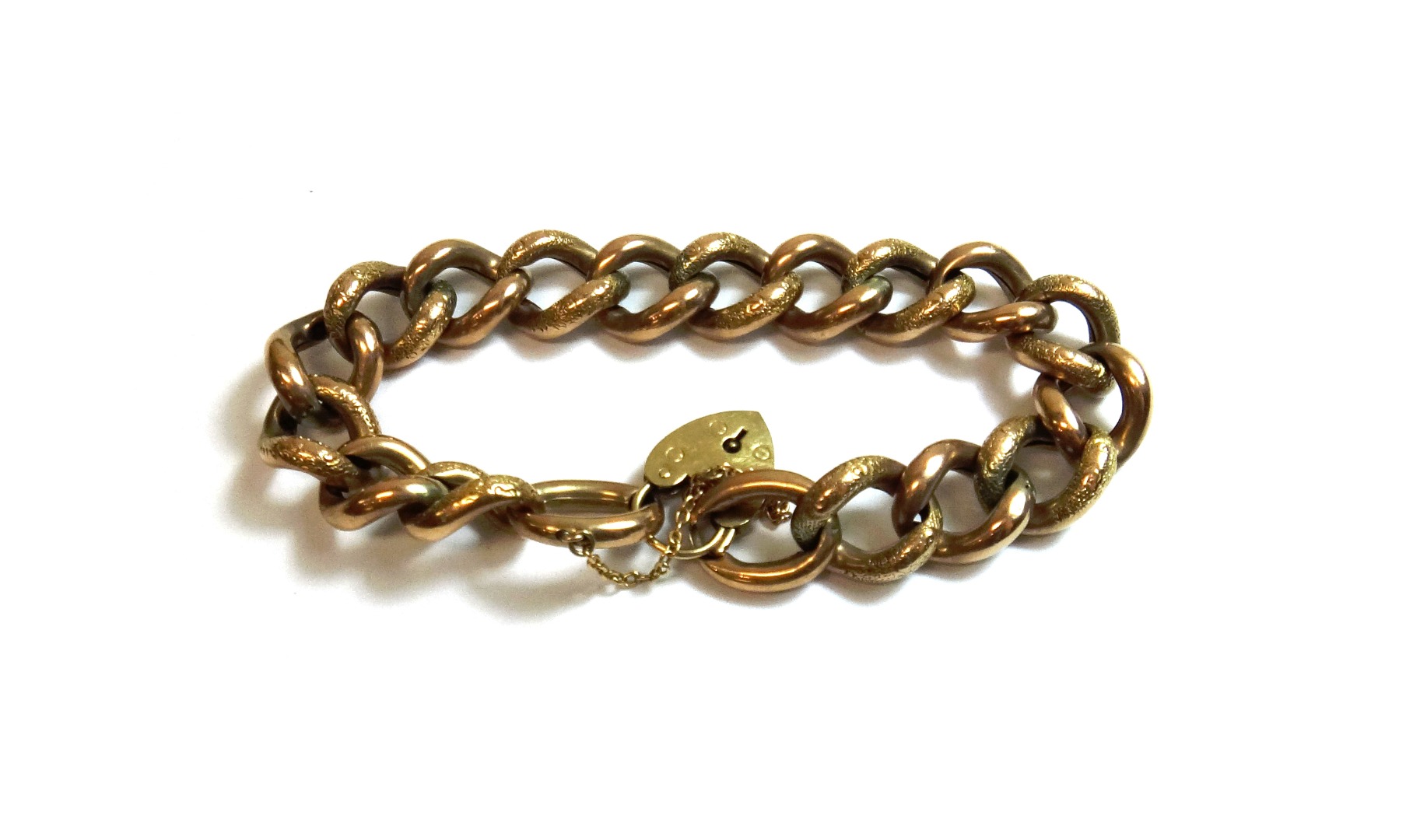 Appraisal: A gold curb link bracelet in an alternating decorated and