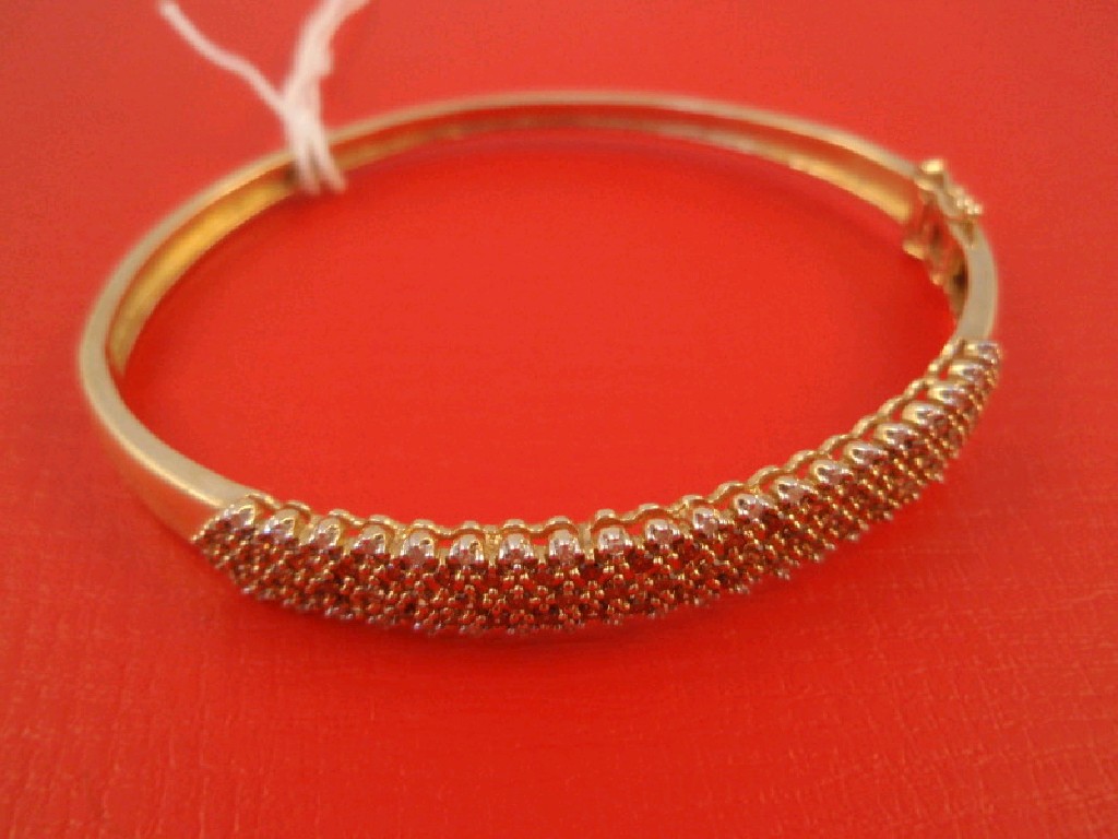 Appraisal: A hinged bangle the top set with bands of tiny