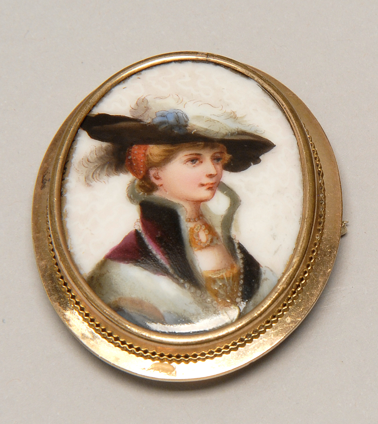 Appraisal: GOLD-MOUNTED PORCELAIN BROOCH th CenturyDepicting a woman wearing a feathered