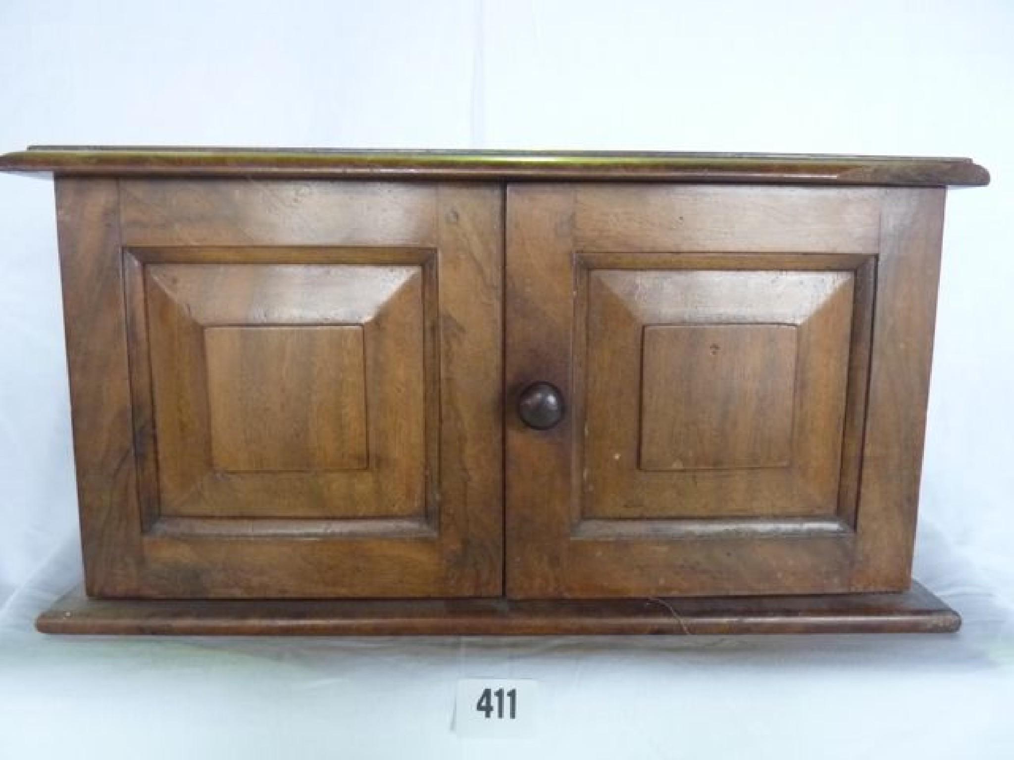 Appraisal: A small walnut cabinet enclosed by two panelled doors to