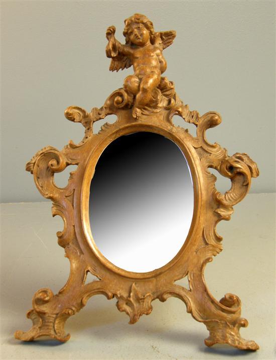 Appraisal: Rococo style walnut oval easel mirror with cherub finial scroll