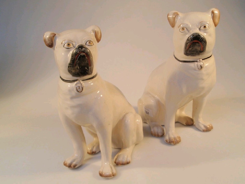 Appraisal: A pair of pottery seated pugs with black red muzzles