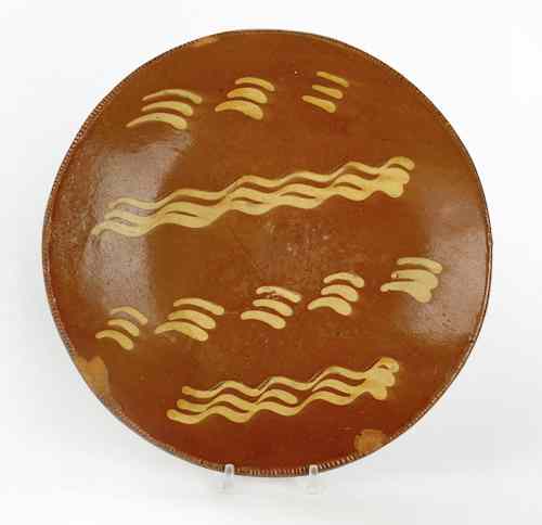 Appraisal: Pennsylvania redware charger th c with yellow slip wavy line