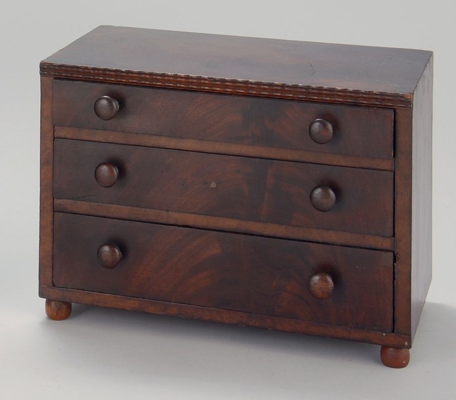 Appraisal: MINIATURE THREE-DRAWER CHEST th CenturyIn pine with mahogany veneers Turned