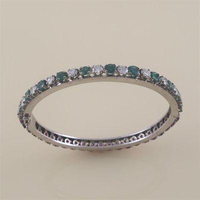 Appraisal: A ruby diamond and emerald set hinged white gold bangle