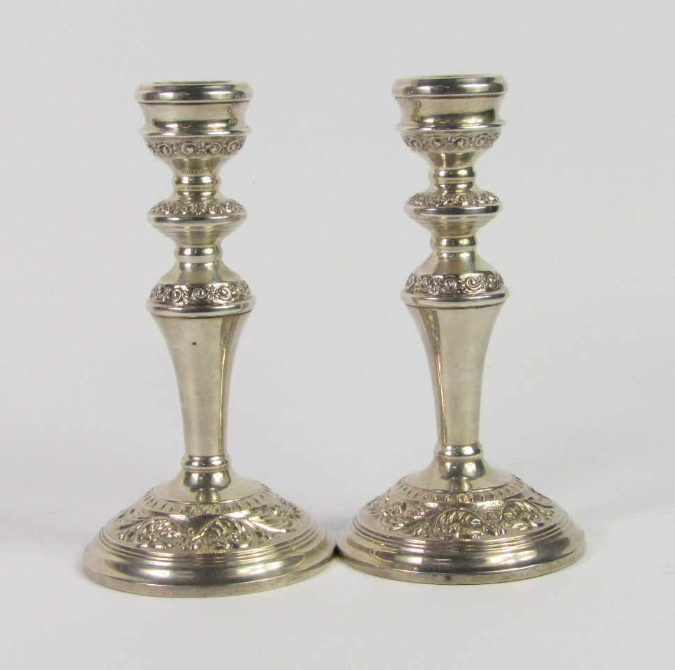 Appraisal: A pair of silver baluster candlesticks with embossed foliate decoration