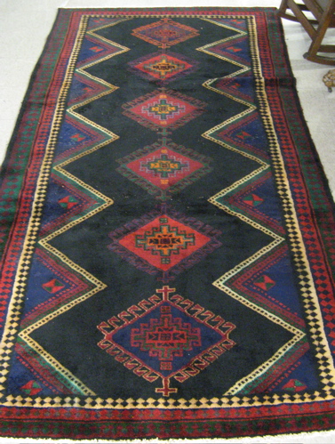 Appraisal: PERSIAN TRIBAL CARPET centering a column of six diamond-shaped latch-hook