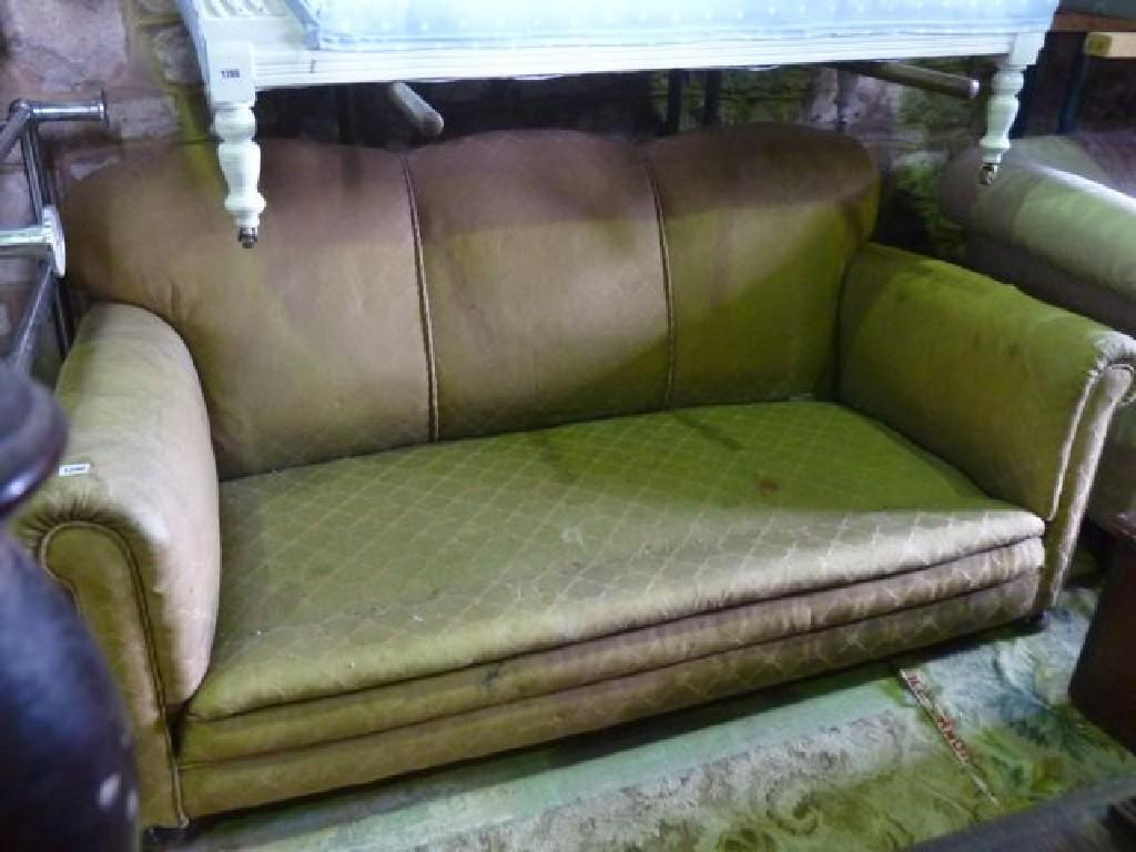 Appraisal: An Edwardian three seat sofa with shaped outline rolled arms