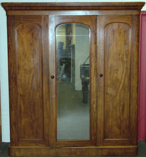 Appraisal: A Victorian mahogany triple wardrobe the rounded cornice above glazed