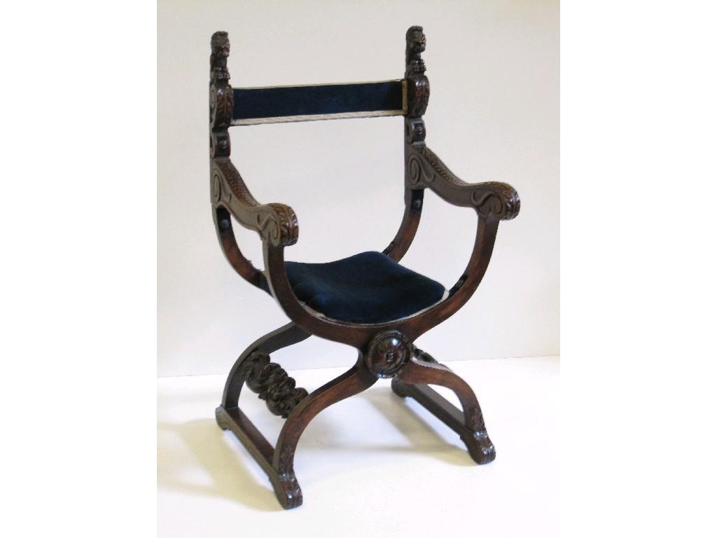 Appraisal: A carved oak X-frame Armchair with gargoyle finials carved acanthus