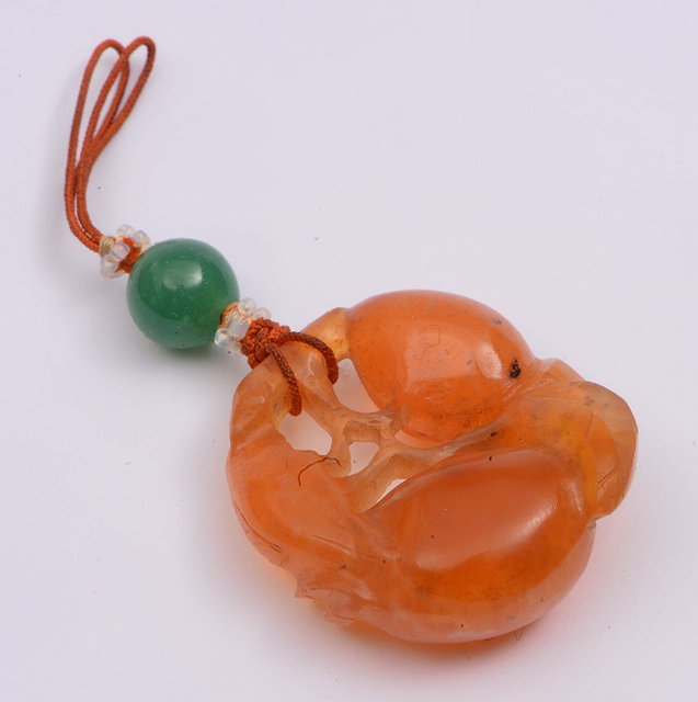 Appraisal: A Chinese orange red chalcedony pendantlate th Centurycarved as peaches