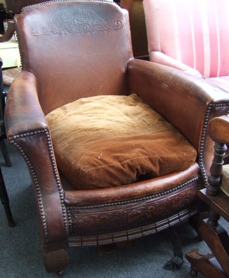 Appraisal: A mid th century embossed leather armchair with outswept studded